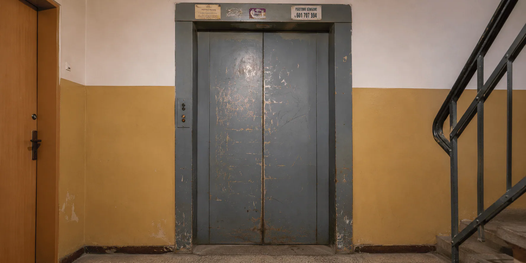 old deteriorating elevator interior with worn buttons and panels, showing signs of age and malfunction, industrial setting